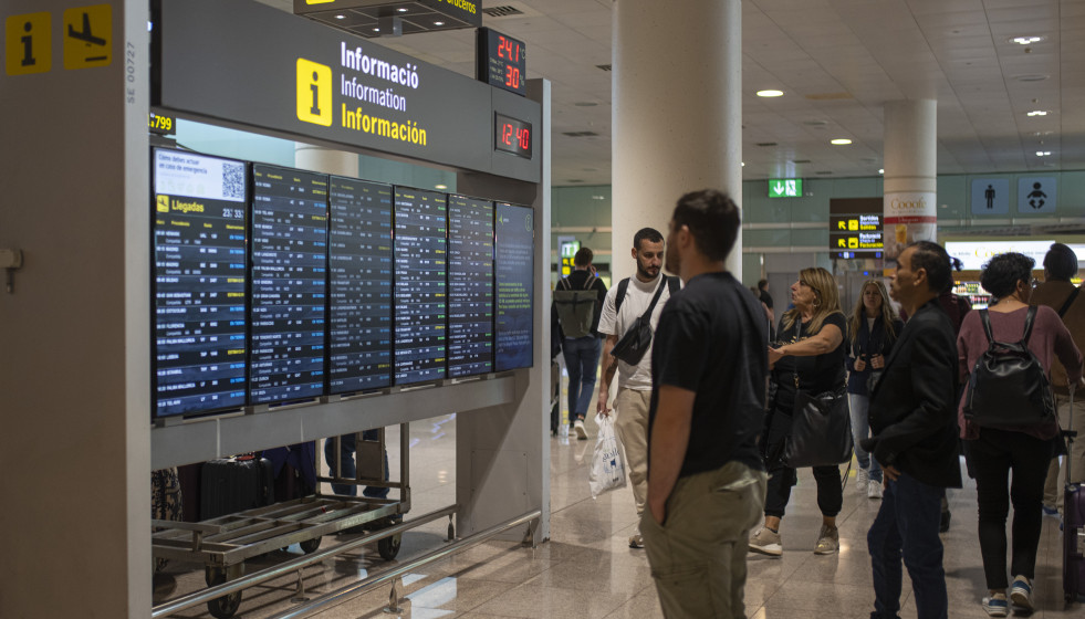 Archivo - Varias personas observan un panel de llegadas en el aeropuerto de Barcelona, a 4 de noviembre de 2022, en Barcelona, Catalunya (España).